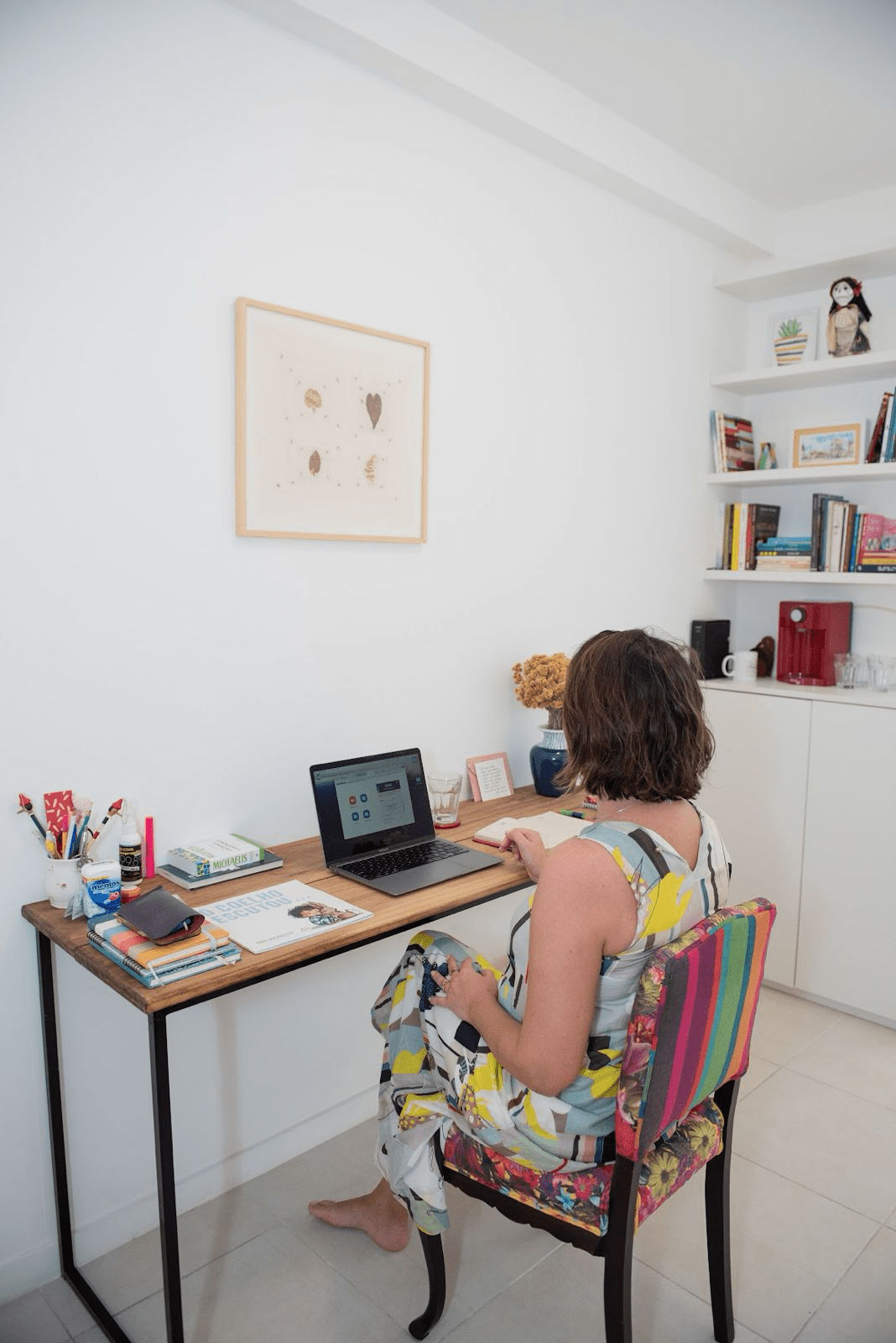 Christine em seu espaço de trabalho, cercada de livros e objetos pessoais